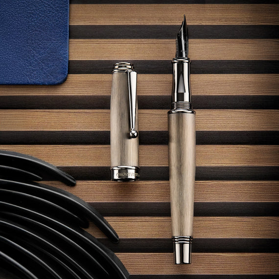 Fountain pen on a wooden surface with a blue object and black items in the foreground